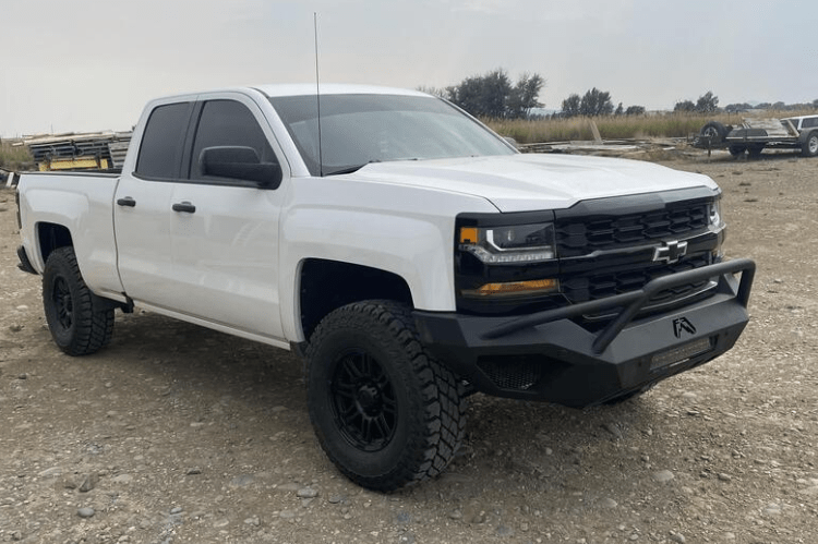 White Chevy Silverado 1500 2016-2018 parked in field with Fab Fours Vengeance Front Bumper Pre-Runner Guard.