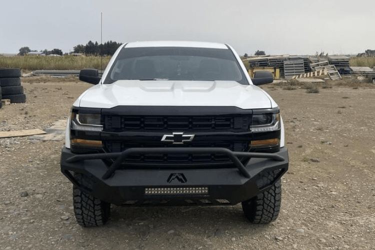 White Chevy Silverado 1500 2016-2018 parked in field with Fab Fours Vengeance Front Bumper Pre-Runner Guard.